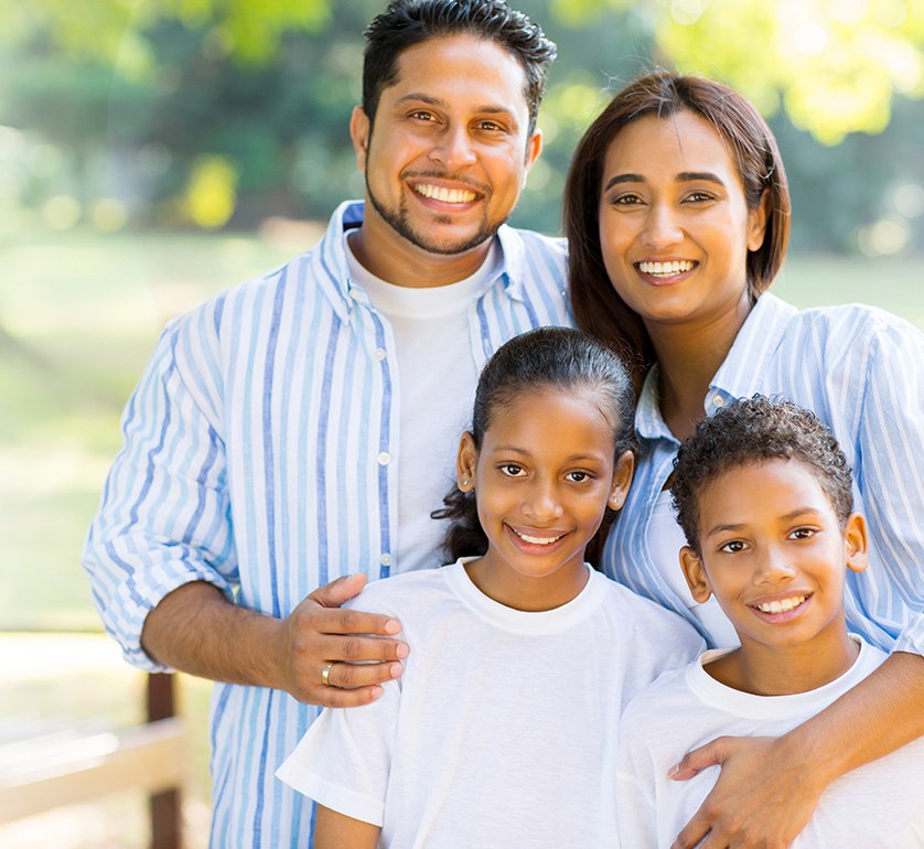 A family of four smiling together, patients of Smile 4U Family Dental Clinic, Kurla
